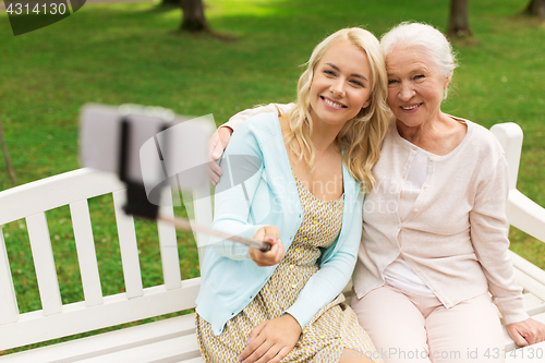 Image of daughter and senior mother taking selfie at park