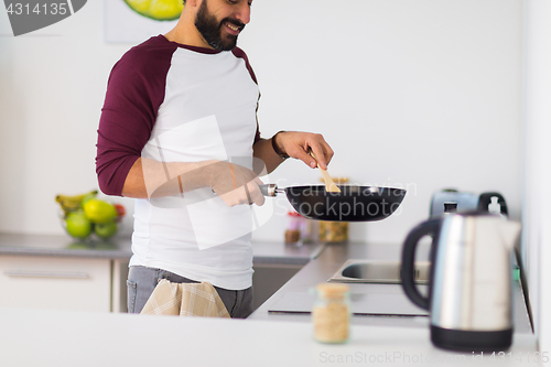 Image of man with frying pan cooking food at home kitchen