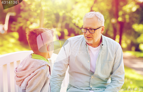 Image of grandfather and grandson talking at summer park