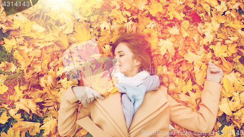 Image of beautiful happy woman lying on autumn leaves