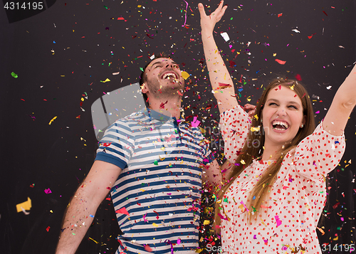 Image of couple blowing confetti in the air isolated over gray