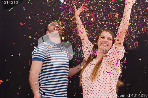 Image of couple blowing confetti in the air isolated over gray