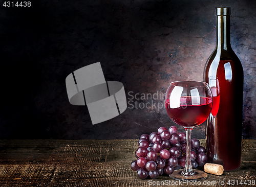 Image of Glass of red wine with grapes and bottle