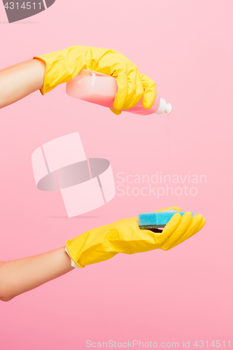 Image of The woman\'s hand cleaning on a pink background. Cleaning or housekeeping concept