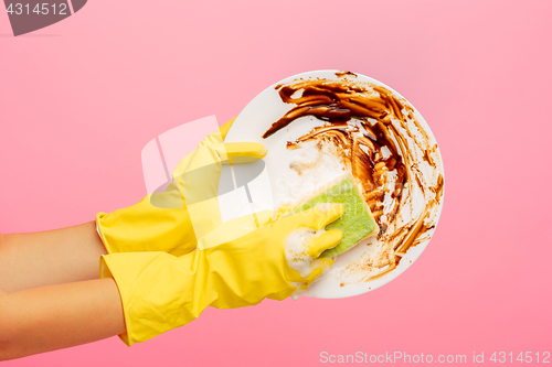 Image of Hands in yellow protective gloves washing a plate