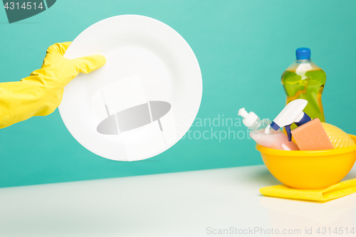 Image of Hands in yellow protective gloves washing a plate