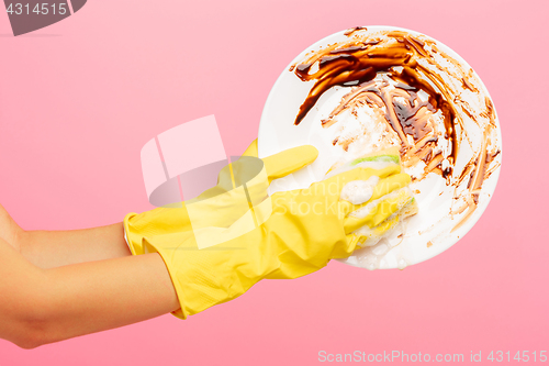 Image of Hands in yellow protective gloves washing a plate