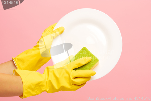 Image of Hands in yellow protective gloves washing a plate