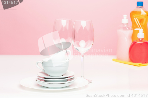 Image of Several plates, a kitchen sponges and a plastic bottles with natural dishwashing liquid soap in use for hand dishwashing.