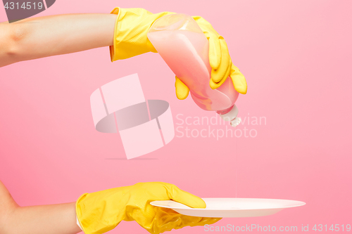 Image of Hands in yellow protective gloves washing a plate