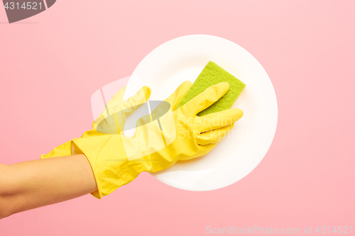 Image of Hands in yellow protective gloves washing a plate