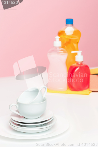 Image of Several plates, a kitchen sponges and a plastic bottles with natural dishwashing liquid soap in use for hand dishwashing.