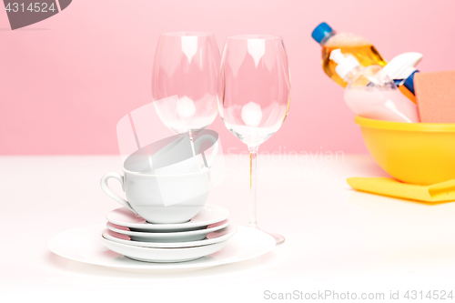 Image of Several plates, a kitchen sponges and a plastic bottles with natural dishwashing liquid soap in use for hand dishwashing.