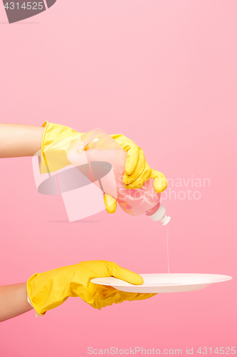 Image of Hands in yellow protective gloves washing a plate