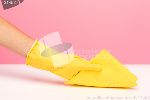 Image of The woman\'s hand cleaning on a pink background. Cleaning or housekeeping concept