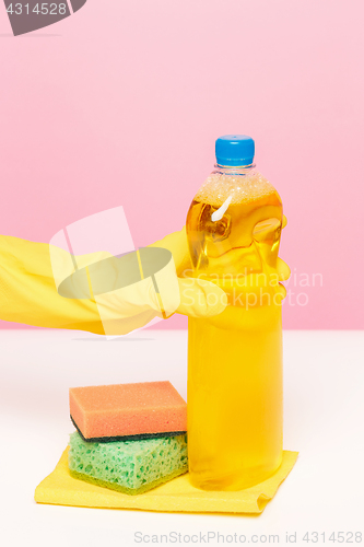 Image of The woman\'s hand cleaning on a pink background. Cleaning or housekeeping concept