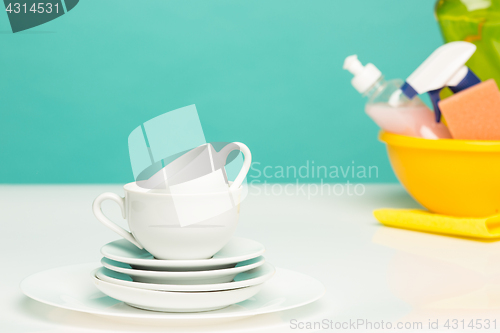 Image of Several plates, a kitchen sponges and a plastic bottles with natural dishwashing liquid soap in use for hand dishwashing.