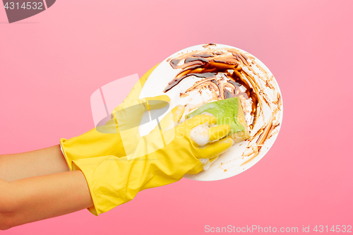 Image of Hands in yellow protective gloves washing a plate