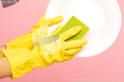 Image of Hands in yellow protective gloves washing a plate