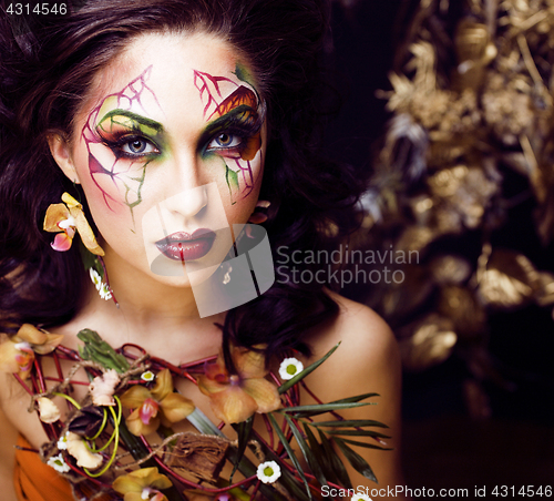 Image of beauty woman with face art and jewelry from flowers orchids close up