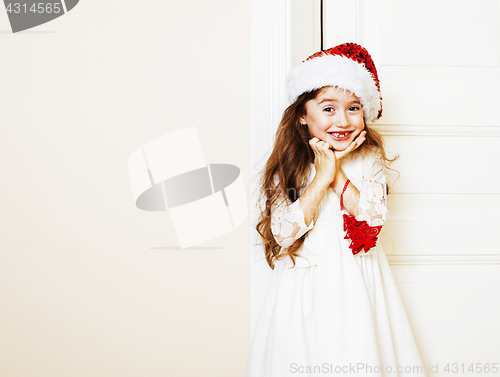 Image of little cute girl in santas red hat waiting for Christmas gifts. 