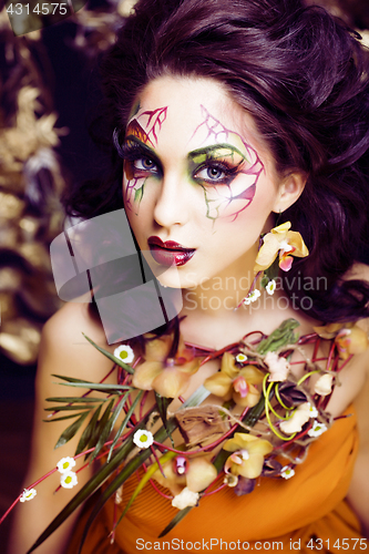 Image of beauty woman with face art and jewelry from flowers orchids clos