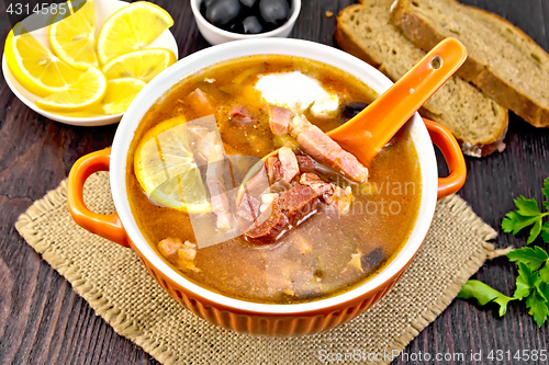 Image of Solyanka with spoon in bowl on dark board