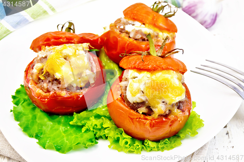 Image of Tomatoes stuffed with meat and rice with lettuce in plate on boa