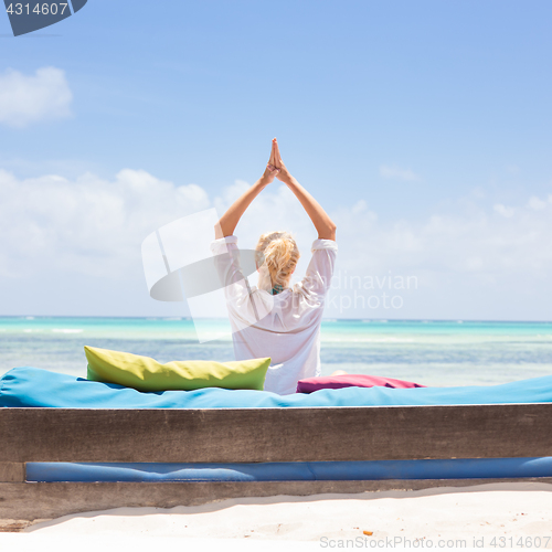 Image of Relaxed woman in luxury lounger, arms rised, enjoying summer vacations on beautiful beach.