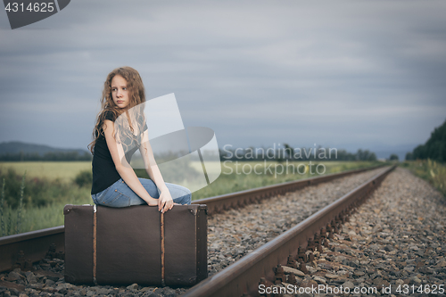 Image of Portrait of young sad ten girl standing with suitcase outdoors a