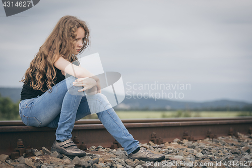 Image of Portrait of young sad ten girl sitting outdoors at the day time.