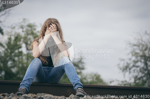 Image of Portrait of young sad ten girl sitting outdoors at the day time.