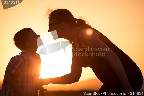 Image of Mother and son walking on the field at the sunset time.