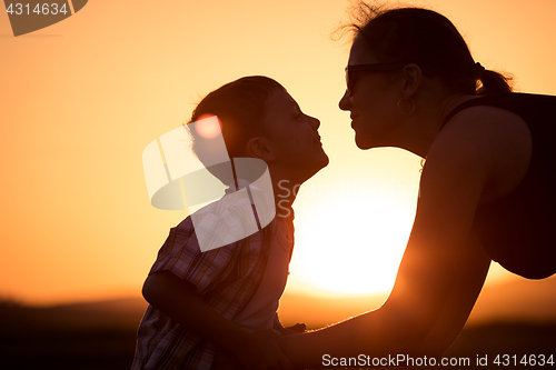 Image of Mother and son walking on the field at the sunset time.