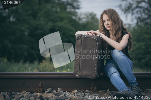 Image of Portrait of young sad ten girl standing with suitcase outdoors a