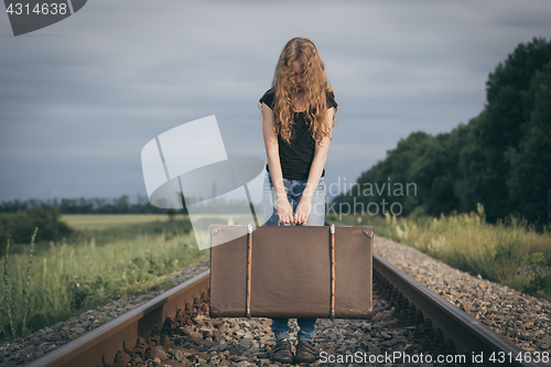 Image of Portrait of young sad ten girl standing with suitcase outdoors a