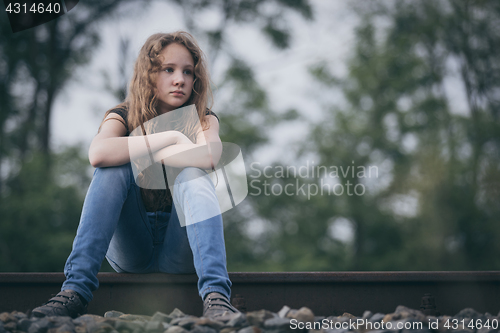 Image of Portrait of young sad ten girl sitting outdoors at the day time.