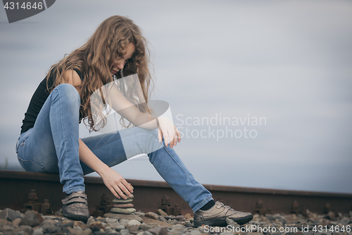 Image of Portrait of young sad ten girl sitting outdoors at the day time.