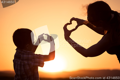 Image of Mother and son walking on the field at the sunset time.