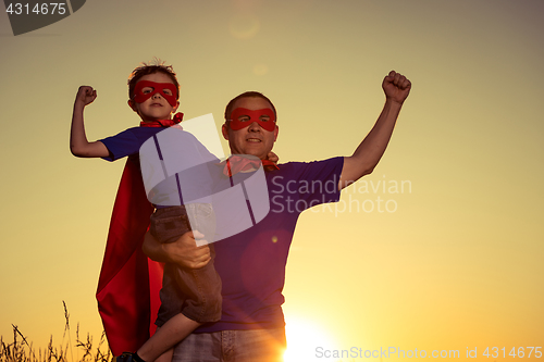 Image of Father and son playing superhero at the sunset time.