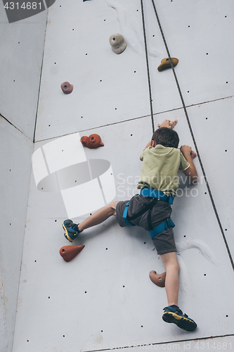 Image of little boy climbing a rock wall outdoor.