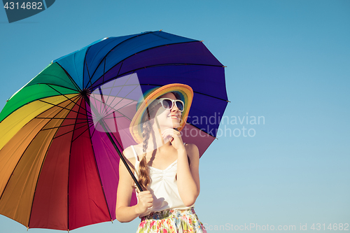 Image of teen girl with umbrella standing on the beach at the day time.