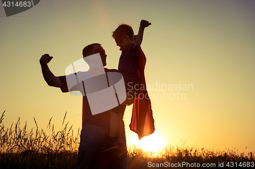 Image of Father and son playing superhero at the sunset time.