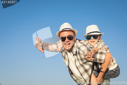 Image of Father and son playing on the field at the day time.