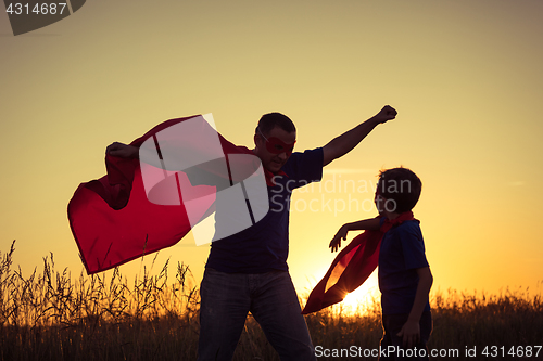 Image of Father and son playing superhero at the sunset time.