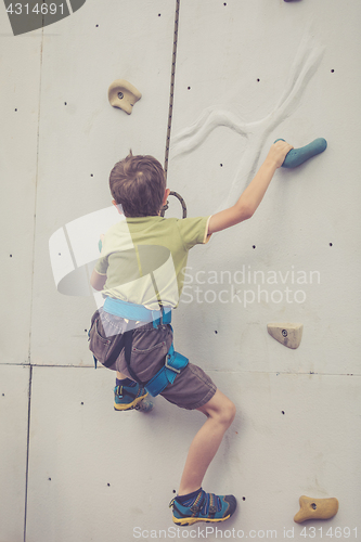 Image of little boy climbing a rock wall outdoor.