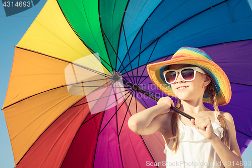 Image of Little girl with umbrella standing on the beach at the day time