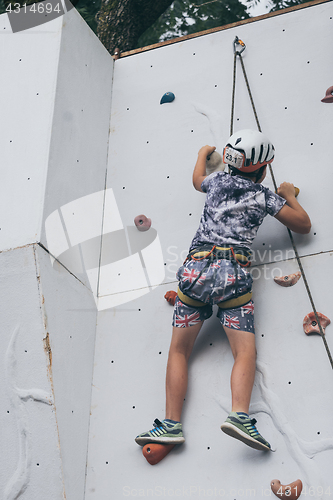 Image of little boy climbing a rock wall outdoor.