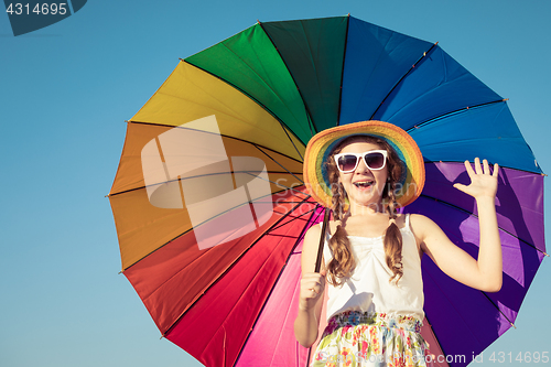 Image of teen girl with umbrella standing on the beach at the day time.