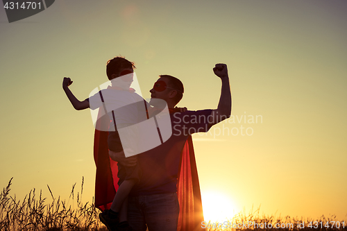 Image of Father and son playing superhero at the sunset time.